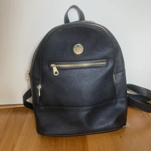 Väska från  Accent - Svart DonDonna väska från Accent som jag köpte för flera år sedan men har inte använts de 3 senaste åren. Den har tre fickor utan på väskan och en innanför väskan. Den är i bra skikt och tål mycket vikt. Har flera bilder! Den har också band så man kan ändra längden på den. 