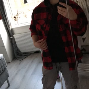 Röd/svart skjorta med luva - Nästan oanvänd. Bra skick. Skjorta med svart luva och möjlighet att vika upp armarna.