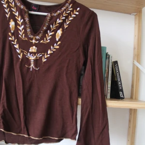 70tals blus  - Blus med stretch. Brun med blommigt insytt mönster. Skulle säga att den passar en XS/S. 
