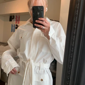 Vit skjortklänning 💖 - Vit klänning, helt oanvänd med prislapp kvar! Storlek 34 men stor i storleken. Dragkedja hela vägen och bälte man kan anpssa efter midjan! Passar perfekt som studentklänning😍