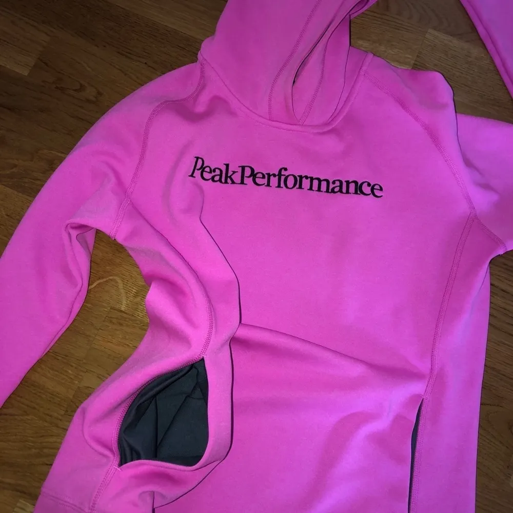 Skrik rosa peak performance tröja med fickor på framsidan samt luva på baksidan. Är i storlek s men är i storlek mellan xs-s. Helt ny pga för liten i storlek, nyskick. Vid frågor hör av dig! . Hoodies.