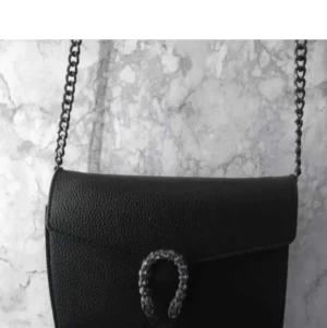 Väska  - Svart väska med väldigt snygg detalj vid öppningen. Tyvärr är den aldrig använd då jag redan har en likadan. 66kr för spårbart eller 45kr för blått kuvert 