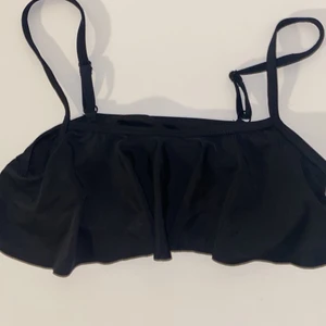 Bikini överdel - En svart bikiniöverdel med volang, i storlek 146/152.