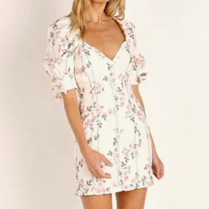 Klänning från märket  For Love & Lemons - Klänning från  For Love & Lemons - ”Rose Stripe Mini Dress Ivory”.                                                            Klänningen är somrig med blommotiv och har en djup V-ringning. Materialet är väldigt bekvämt och har lite stredge som kramar åt på ett mjukt sätt.  På bilden har jag den faktiskt bak och fram med dragkedjan framtill då den blev lite för V-ringad för min del. Använd en gång. Lapp med storlek finns inte men är mellan 36-38 skulle jag tro. Ordinarie pris ligger runt ca 2000:-. 