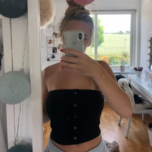 Svart top utan band  - Knapparna går inte att öppnas utan är endast en del av designen. Den sitter tajt över brösten så den åker inte ner. 