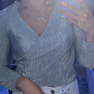 Silver omlott tröja - En omlottströja som är i storlek 146/152 MEN ändå funkat på mig som har S i storlek så kan säga mer att det är XS/S. Frakten tillkommer