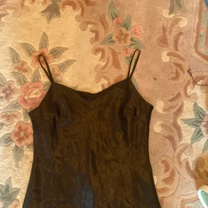 Linne svart blankt - Ett svart linne i material som gör det blankt. Säljs då linnet inte passar över brösten. Snyggt linne som passar till väldigt mycket och fint på. 100% polyester