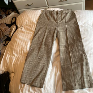Kostymbyxor  - Beiga rutiga kostymbyxor. Lite slitet vid öppningen som kan ses på bild men inget som påverkar byxan
