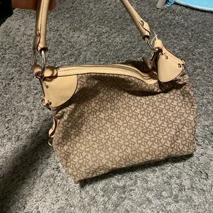 DKNY väska - DKNY väska beige, nypris 3499:- . Har tyvärr fått ett hål under väskan på kanten ( se bild )