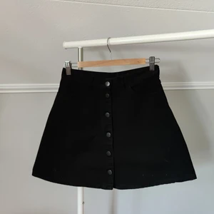 Knappkjol - Snygg svart jeanskjol men knappar från Monki. Använd men fortfarande i fint skick!