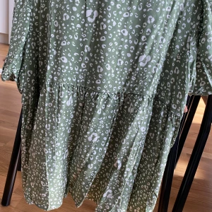 Blus  - Grön peblumblus med leopardmönster. Korta ärmar med ”puff”. 