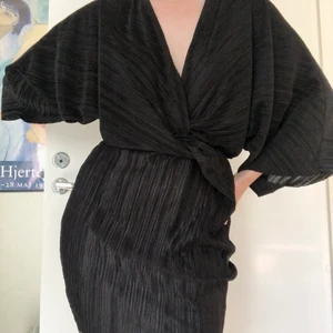 Svart Omlottklänning med knut  - Omlottklänning med knut i mitten, stretchigt och skönt material. Originalpriset 400kr 