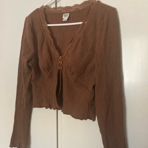 Urban Oufitters kofta! - Brun croppad kofta från Urban Outfitters! Endast använd en gång. Det står att det är L, men skulle säga att det är en M. Den skulle nog även passa S. Möts i Stockholm, annars står köparen för frakt. 