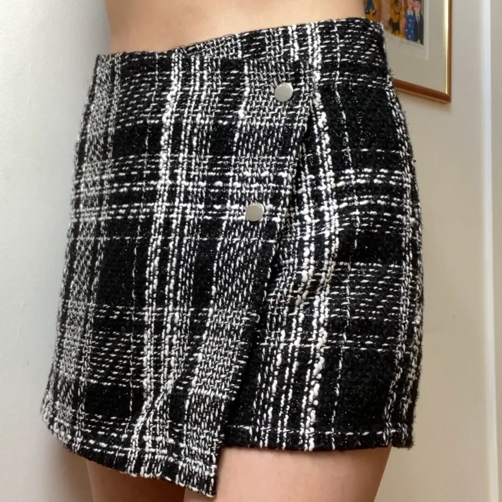 Ett par shorts med illusion av att se ut som en kjol framtill med detaljer av silvriga knappar. Aldrig använd och den är köpt på New Yorker.. Shorts.