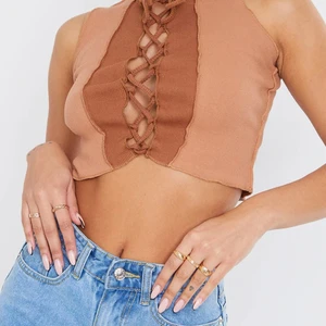 Croptop med snörning  - Brun/beige croptop i stretchigt tyg strl 34. Prislappar och orginalförpackning kvar, säljer pga för liten storlek. Från PrettyLittleThing.