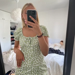 Grön blommig klänning. Strl S - Tunn och luftig klänning som inte är använd, bara provad! Klänningen går att justera genom att dra åt snörena.