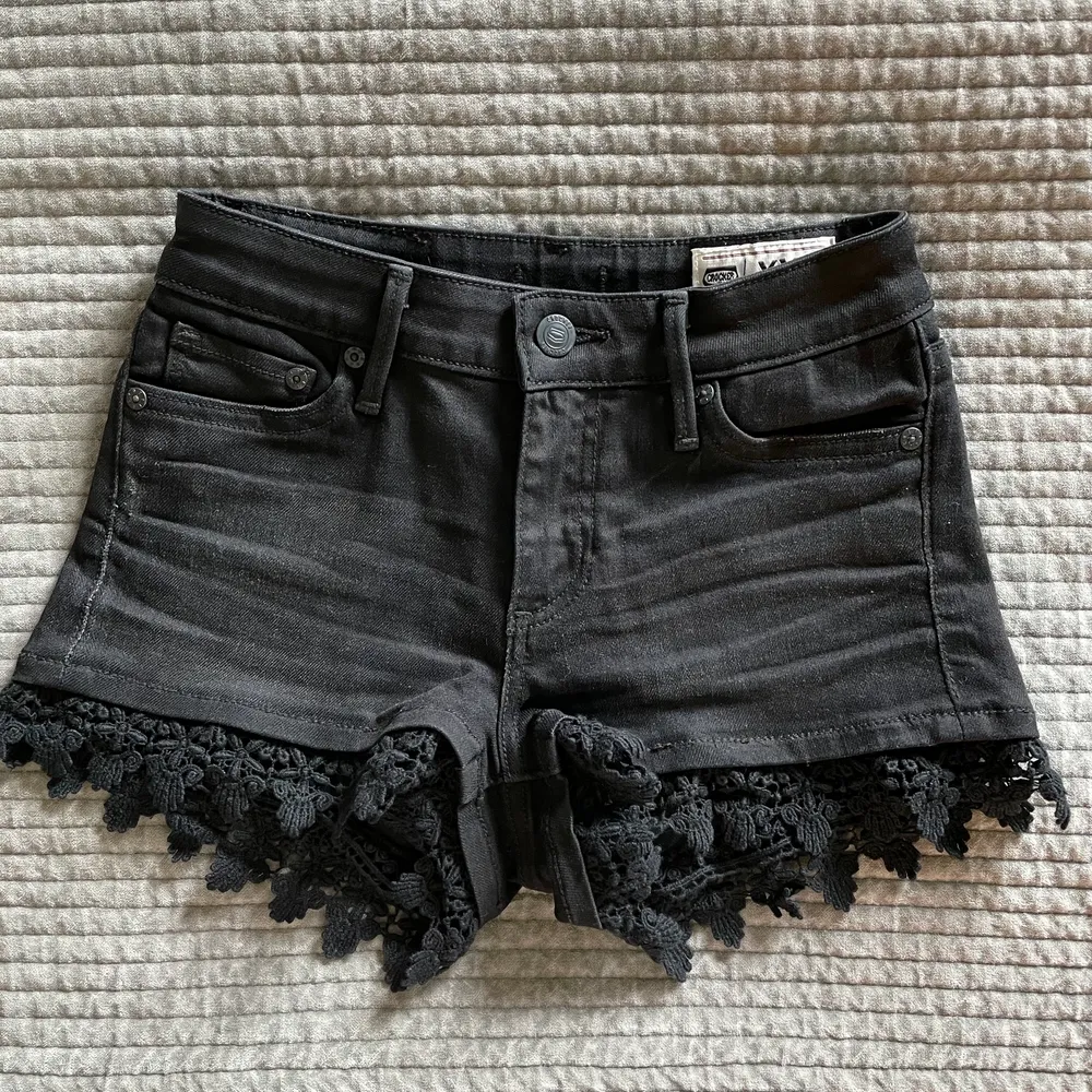 Svarta jeansshorts från Crocker med fin spetsdetalj vid benen, storlek XXS. På bilderna ser de mer gråa ut än de är i verkligheten. Mycket fint skick, säljer eftersom de tyvärr är för små för mig. Fraktkostnad tillkommer 🌼. Shorts.