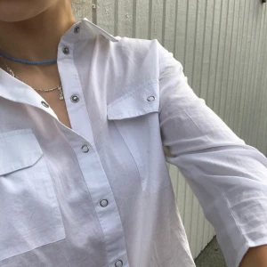 Vit skjorta strl S - Fin vit skjorta med fickor och rosetter. Rosetterna går att justera så att man får dem som man vill. Skjortan är i storlek S men skulle nog kunna passa XS också. 