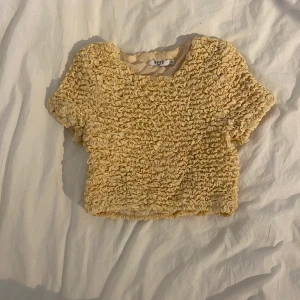 Gul croppad topp - Aldrig använd. Jättefin topp till ett par ljusa högmidjade jeans i sommar/vår! Storlek 38. Går att både klä upp och ner. Köparen betalar frakt