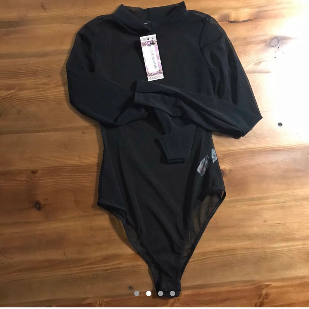 New with tags. Long sleeve black see thru mesh tulle high neck body suit with high cut bikini snap closure. Not really stretchy. Polyester elastane blend. Tag size US 6 UK 10 EU 38.  Brand new item. Made in UK. Happy to bundle. Will gladly take more pics.  Smoke and pet free storage space. No other flaws to note.. Övrigt.
