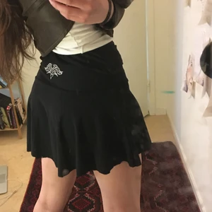 Kort kjol med trampstamp - Asnajs kort svart y2k-kjol med ett tribal-tramp stamp i svanken! Jag har klippt den kortare så sömmen är inte 100% rak men oavsett fett snygg!!