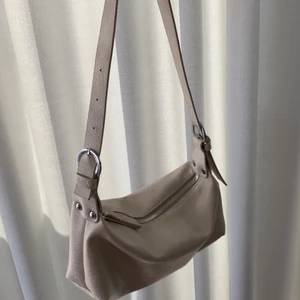 Baguetteväska - Beige i läderimitation. Oanvänd!! Bandet är reglerbart! Mycket rymlig! Köptes på Amazon för ca 25 USD!