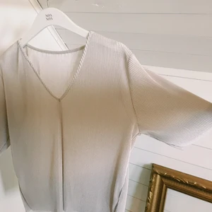 Plisserad topp - Plisserad topp i skimrande gräddvit. Endast använd 1 gång! Passar xs/s/m beroende på hur man vill att den ska sitta. Frakt tillkommer 