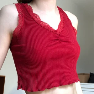 Rött linne med spets  - Superfint ribbat, rött, kort linne med spets. Passar perfekt nu till sommaren! Linnet är också stretchigt så jag skulle gissa på att det passar på en S också! 