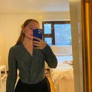 Grön skimmrig body - Plagget är ifrån Gina Tricot. Storlek S. En perfekt finare blus perfekt till fest eller liknande. Tunt och svalt tyg i en body där bakdelen är stringformad. Går att göra mer uringad. Superfin grön skimmrig färg. FRAKTEN ÄR INBAKAD I PRISET 