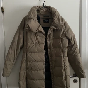 Vinterjacka  - Lång till låren, tight. Håller värmen men är åt det tunnare hållet 