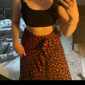 Svart kjol med röda hjärtan - Jätte söt kjol med röda hjärtan, midjan knyts vilket gör att den passar alla från XS-M (eventuellt L också)✨ Hör av dig vid frågor💕