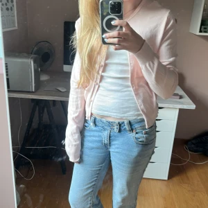 Ljusrosa cardigan från Divided H&M - Supersöt ljusrosa cardigan med rund hals och knappar framtill. Modellen är croppad och har långa ärmar. Perfekt att slänga över ett linne eller t-shirt för en chill och söt look. Tunn och mjuk, passar både till jeans och kjol.