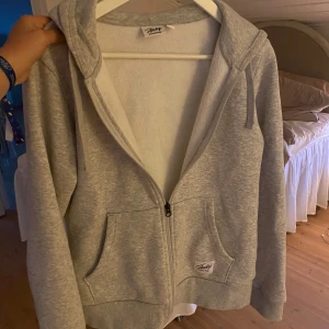 Grå zip hoodie från Andy - Mjuk och basic ljusgrå hoodie från Andy med dragkedja framtill, två stora fickor och huva med snören. Med svarta detaljer. Perfekt för chill dagar eller när du vill ha en enkel och clean look. Klassisk passform och ribbade muddar.❤️ Hör av er vid frågor❤️ pris går att diskutera❤️