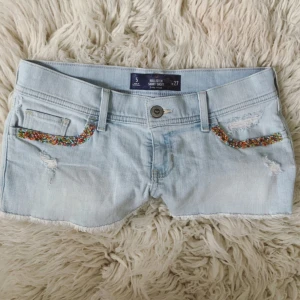 HOLLISTER ljusblåa lågmidjade jeanshorts med pärlor  - Modell: short-short lowrise💞Midja rakt över: ca 39 cm💞Putteliten defekt se sista bild!