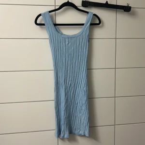 Ljusblå ribbad ärmlös klänning - Supersöt ljusblå kortklänning med ribbad struktur och breda axelband. Klänningen är ärmlös och har en enkel, tight passform som framhäver figuren. Perfekt för varma dagar och enkel att styla med sneakers eller sandaler.