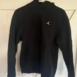Svart Jordan hoodie med logga - Svart hoodie från Jordan med klassisk vit Jumpman-logga broderad på bröstet. Tröjan har huva, känguruficka och långa ärmar. Perfekt för dig som gillar sportig och clean stil. Mjuk och skön bomullsblandning.