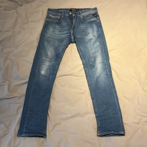 Replay Grover Hyperflex jeans blå 32/32 - Blå Replay Grover Hyperflex jeans med klassisk femficksdesign, dragkedjegylf och snygga slitningar framtill. Jeansen har raka ben och normal passform, tillverkade i stretchigt denim för extra komfort. Perfekta för dig som gillar en avslappnad men stilren look.