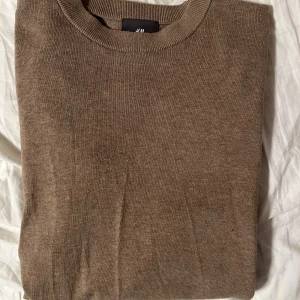 Brun stickad tröja från H&M slim fit - Snygg brun stickad tröja från H&M i slim fit-modell. Perfekt för lager-på-lager och passar till både jeans och chinos. Enkel och stilren design som funkar året runt.