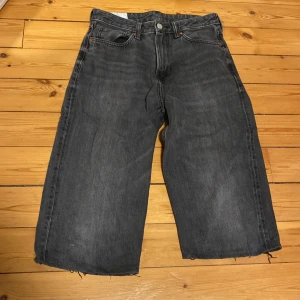 Svarta loose fit jeansshorts H&M - Loose fit jeansshorts/jorts från H&M i svart denim. Modellen är rak och bred för en avslappnad vibe. Klassisk femficksdesign. Perfekta för dig som gillar en baggy och bekväm stil.
