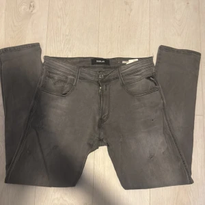 Replay Anbass - Snygga grå jeans från Replay med klassisk femficksdesign och raka ben. Jeansen har diskreta slitningar och svarta detaljer på bakfickorna. Perfekta för dig som gillar en stilren och avslappnad look. Storlek 32/30