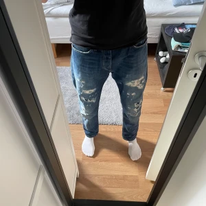 Jack and Jones jeans med slitningar - Säljer ett par blå jeans med coola slitningar och en avslappnad passform. Passformen är 'Erik Anti Fit' vilket är som en regular fit. Perfekta för en avslappnad stil. Kontakta gärna vid frågor 😊