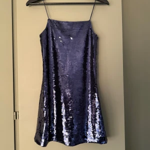 Paljettklänning H&M - Supersnygg mörkblå miniklänning från H&M med tunna axelband och glittriga paljetter över hela klänningen. Perfekt till nästa nyårsfirande. 
