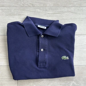Mörkblå pikétröja från Lacoste - Sliten under kragen, inget man ser när man har på sig dock, sen är knappen också lite lös men inget man heller märker vid användning. Hittade ett pyttelitet hål i underarmen men inget man ser eller så! KAN GÅ NER I PRIS VID SANBB AFÄRR
