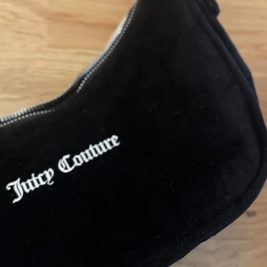Svart axelväska från Juicy Couture - Svart axelväska från Juicy Couture i mjuk sammet. Väskan har justerbart axelband. Inga fläckar eller skador! 