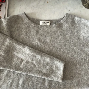 Ljusgrå cashmeretröja från Davida - Supermjuk och stilren ljusgrå tröja i 100% cashmere från Davida. Klassisk rund halsringning och långa ärmar. Perfekt för en clean look.