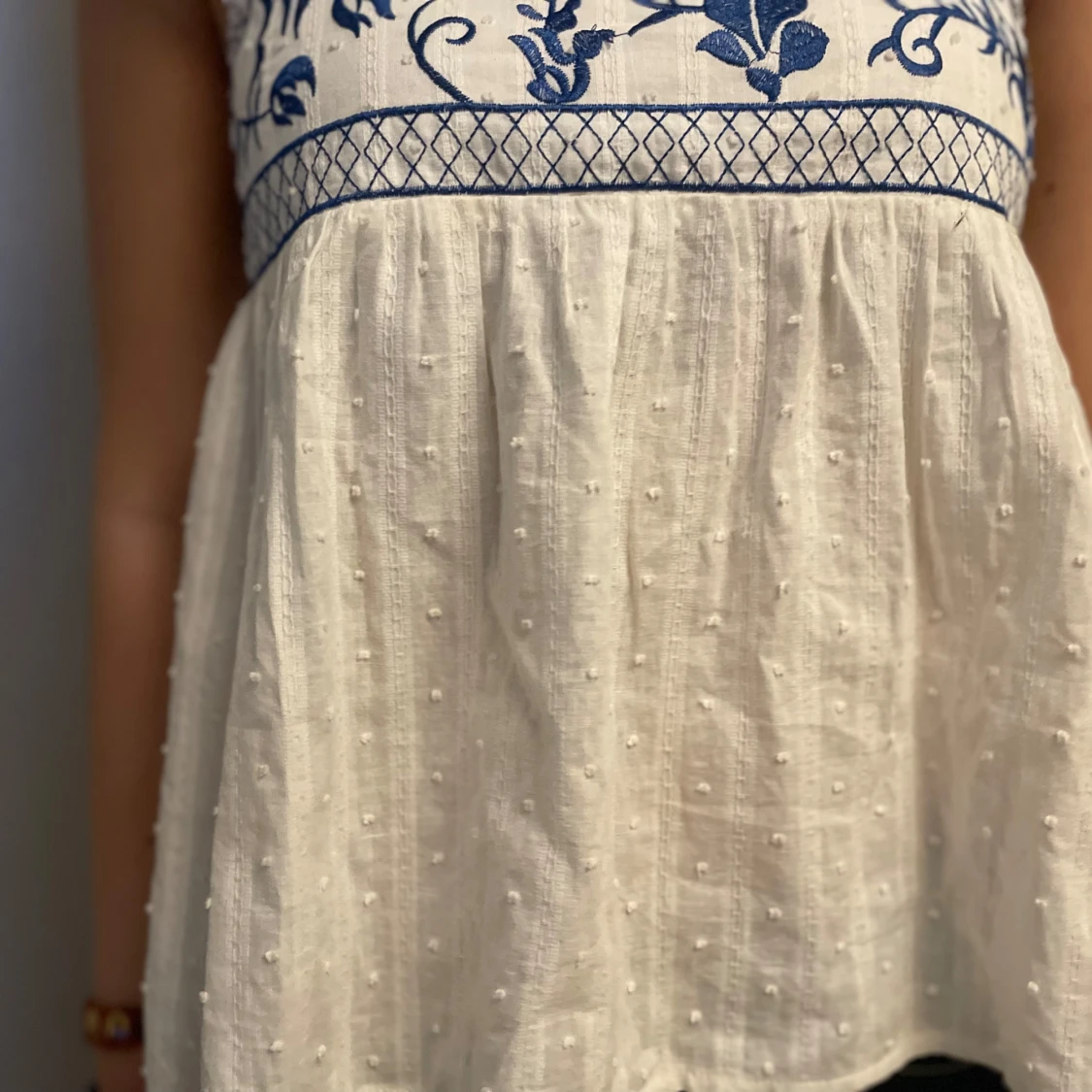 Vit blus med blå broderier och volangärmar