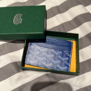 GY korthållare - Säljer en snygg blå korthållare med deras klassiska mönster. Korthållaren har flera fack för kort och är tillverkad i skinn. Perfekt accessoar för dig som vill ha något stilrent och exklusivt i fickan.