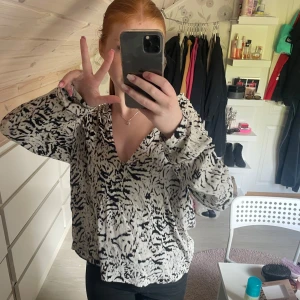 Vit och svart blus med mönster från KappAhl - Säljer en snygg vit blus med svart abstrakt mönster från KappAhl. Blusen har v-ringning och långa ärmar, perfekt för att lyfta din outfit. Skön och luftig modell som passar till många tillfällen.