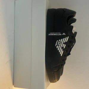 Svarta sneakers från Emporio Armani - Hej! Säljer dessa snygga helt nya Emporio Armani skor då jag fick de i present och inte passar i storlek, skorna kommer med boxen och etiketter finns kvar tveka inte på att höra av er. 