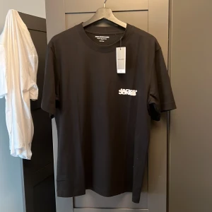 Svart t-shirt från Jack & Jones - Säljer en svart t-shirt från Jack & Jones Core med liten vit logga på bröstet. Klassisk rund halsringning och normal passform. Perfekt basplagg till garderoben. Helt ny med tag kvar.